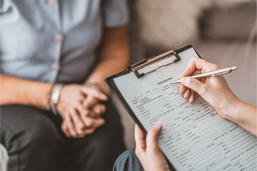 A medical professional takes notes during a consultation with a patient