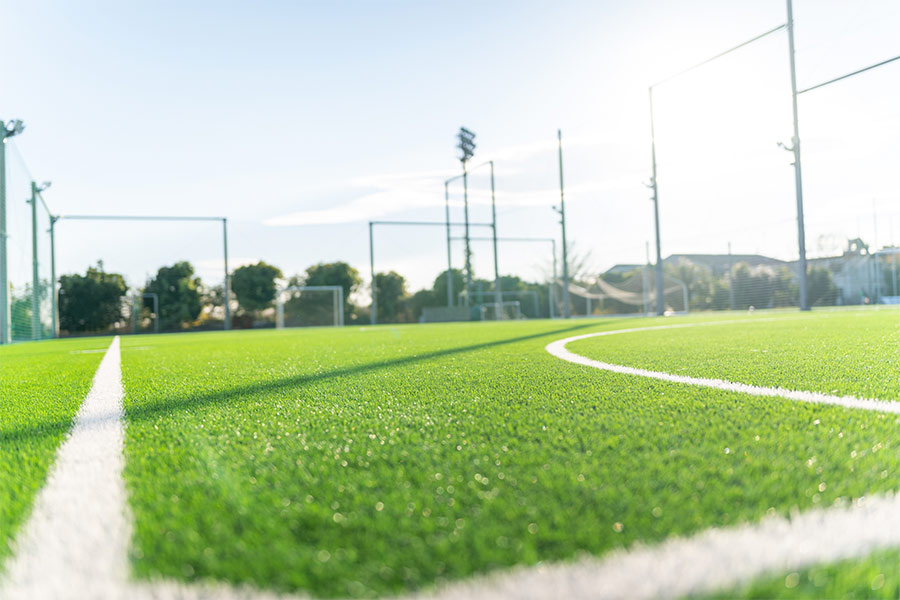 A fenced soccer field is seen on a sunny day