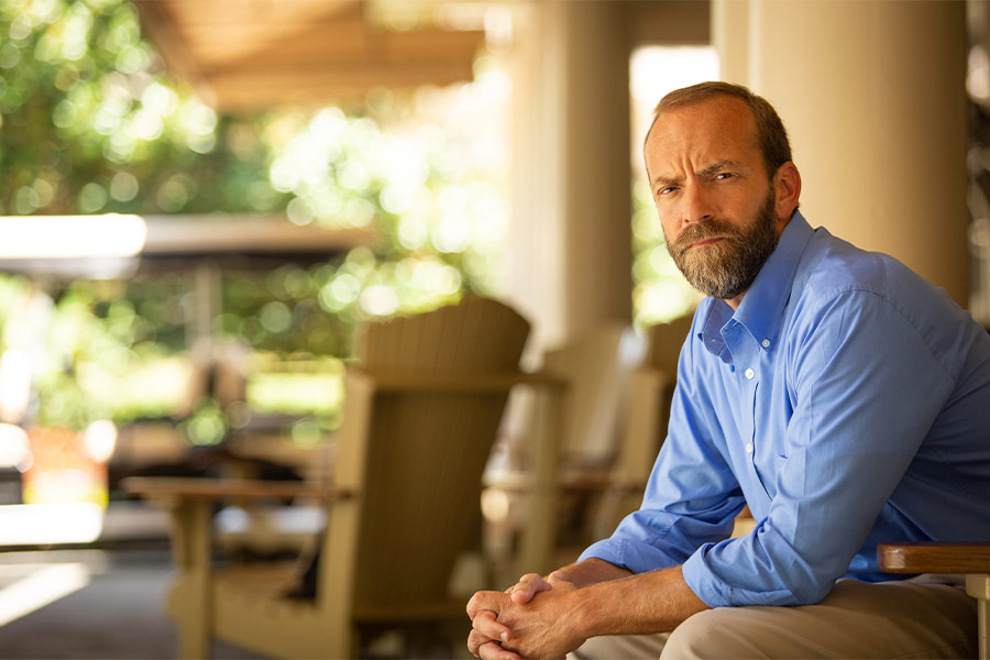 Blaine Adamson of Hands On Originals sits on the porch with a serious expression on his face