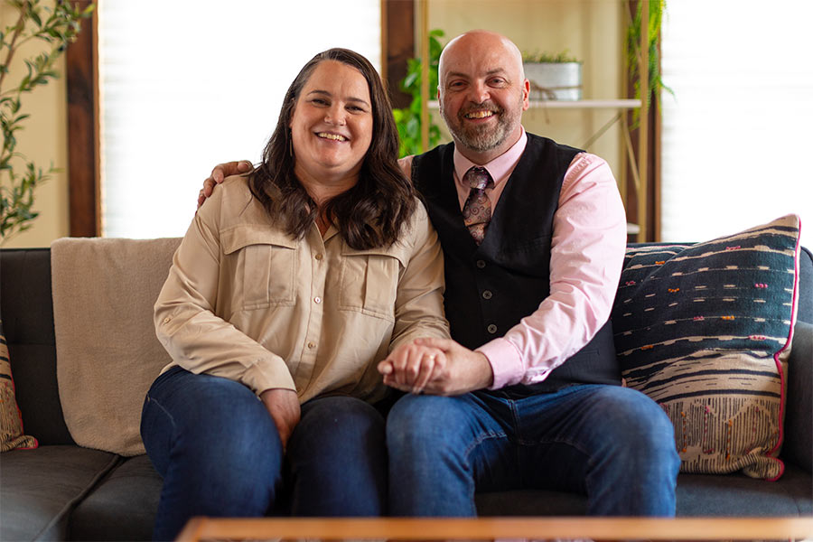 Bryan and Rebecca Gantt hold hands sitting on the couch