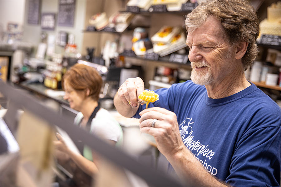 Jack Phillips stands behind the counter at Masterpiece Cakeshop, decorating a cake