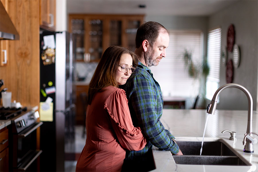 Joe and Serena Wailes embrace as they wash the dishes