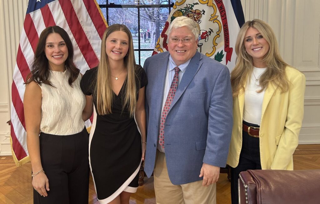 (L to R) Abby Cross, Adaleia Cross, West Virginia Gov. Patrick Morrisey, and women's sports advocate Riley Gaines attend the signing of West Virginia SB 456 into law.
