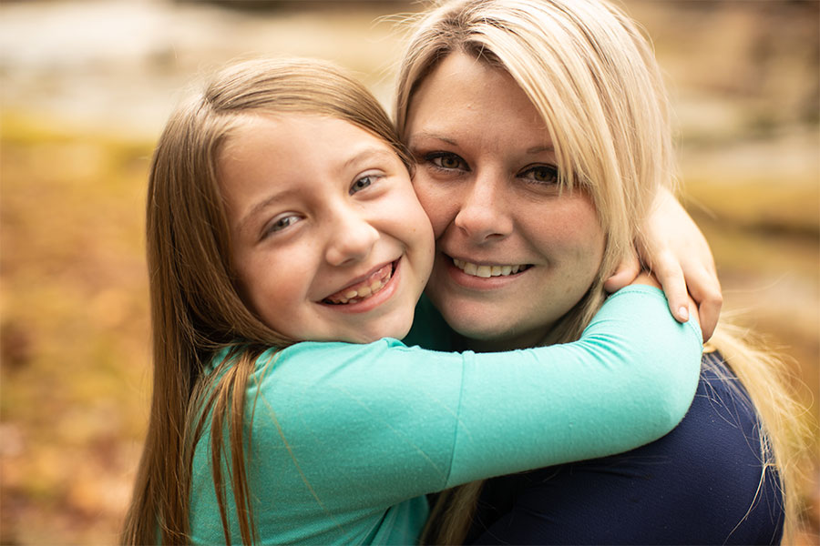 Lydia Booth, left, hugs her mother, Jennifer, as the two smile.