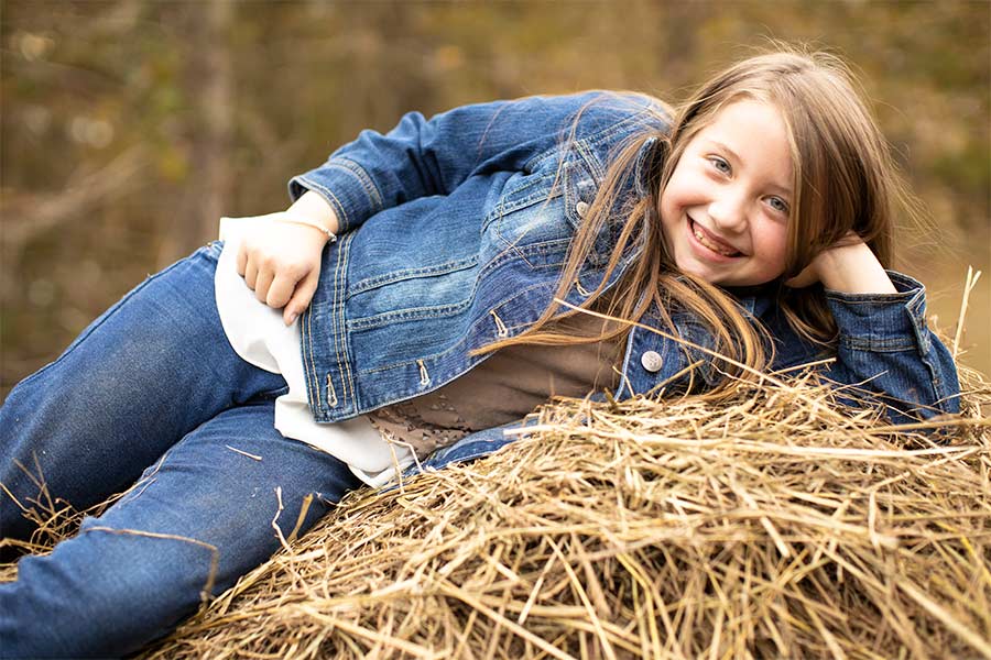 Lydia Booth smiles while lying on a hay bale.
