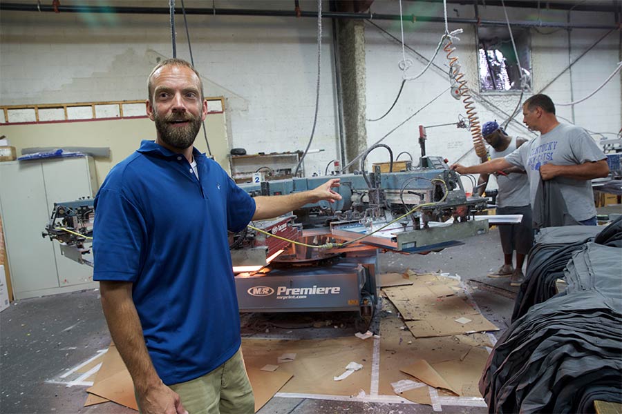 Blaine Adamson gestures toward machinery in a shop.