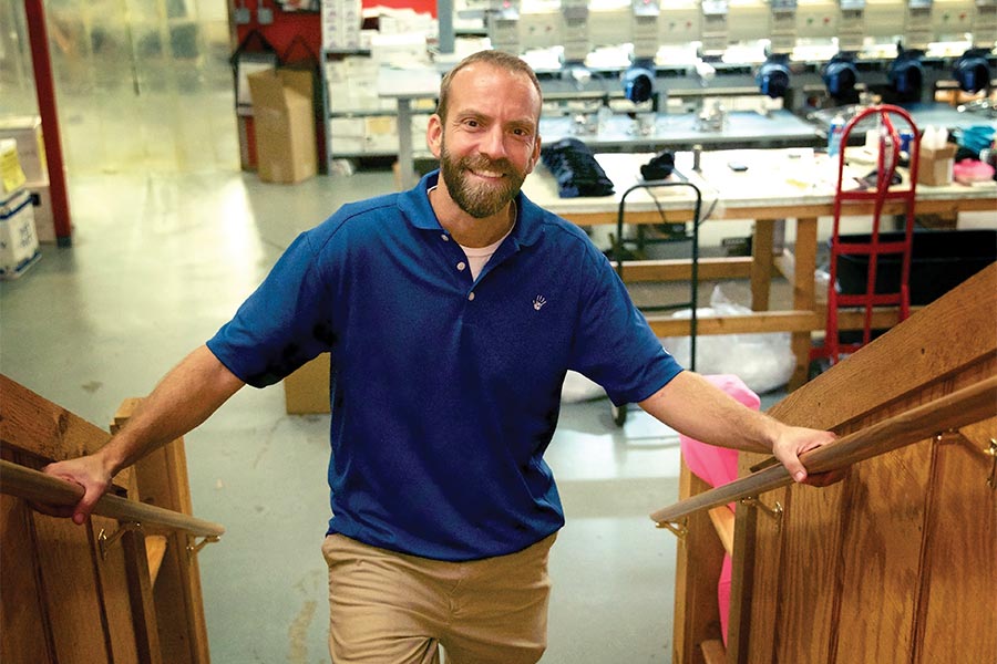 Blaine Adamson stands on the stairs with his hands on the handrails.